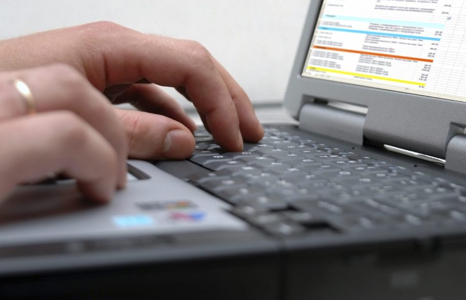 Main en train de taper sur le clavier d'un ordinateur portable.