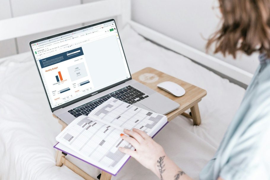Person utilisant un ordinateur portable sur un bureau, feuilletant un carnet.