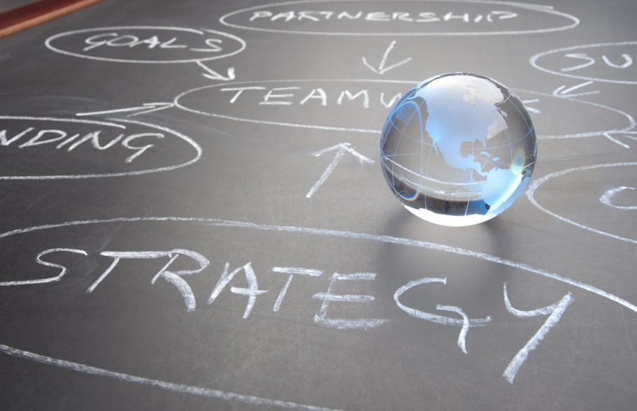 Un globe en verre posé sur un tableau avec des mots-clés liés à la stratégie.