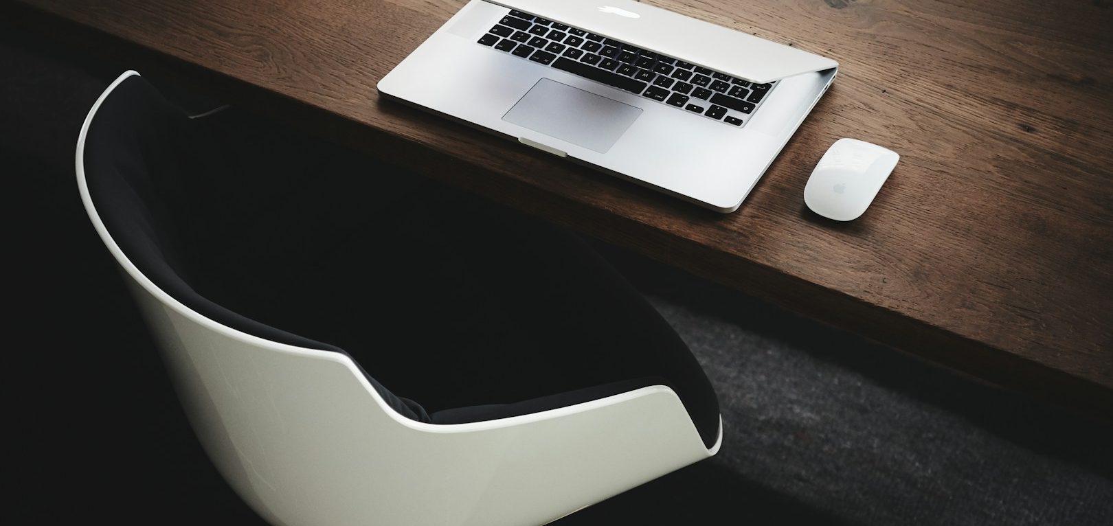 Bureau en bois avec un ordinateur portable et une souris sur une chaise moderne.