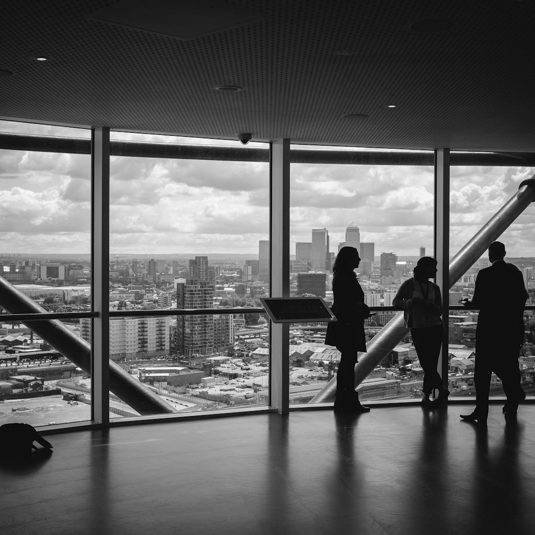Silhouettes de trois personnes devant de grandes fenêtres avec vue sur la ville.