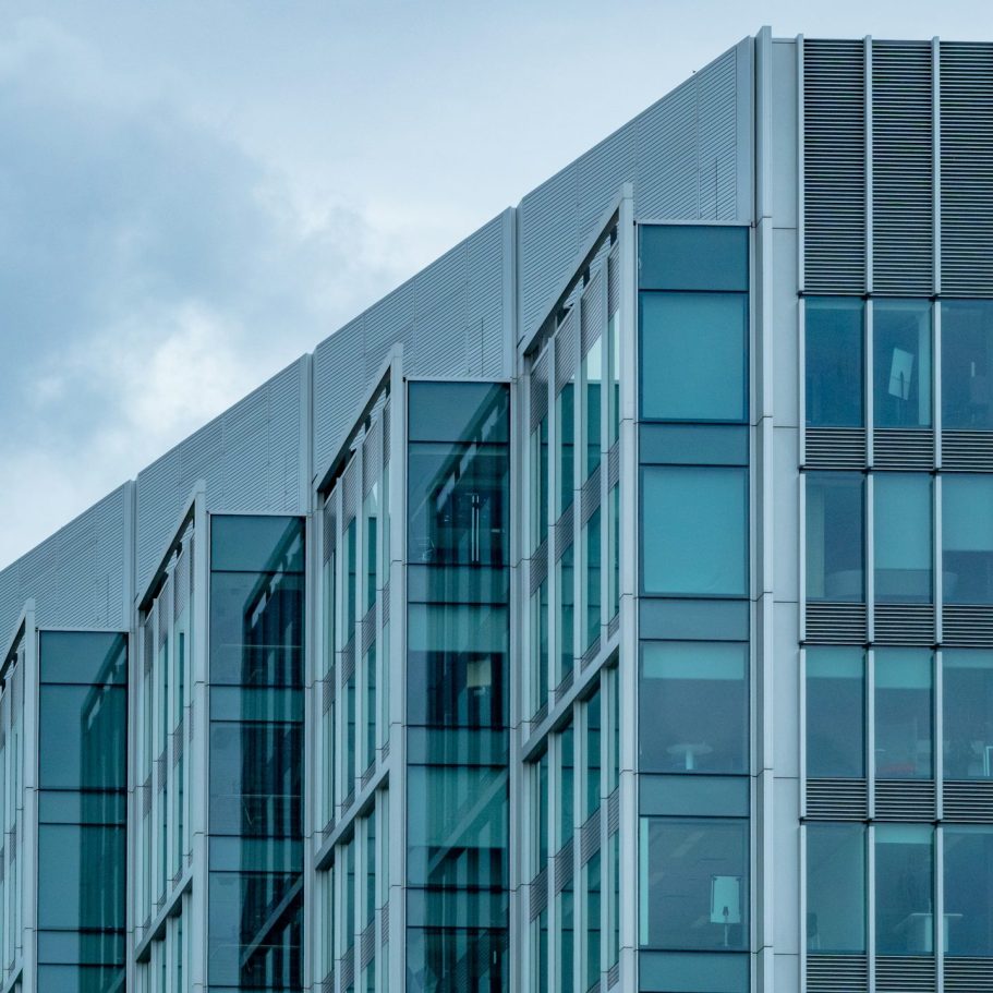Façade d'immeuble moderne avec fenêtres en verre et angles marqué.