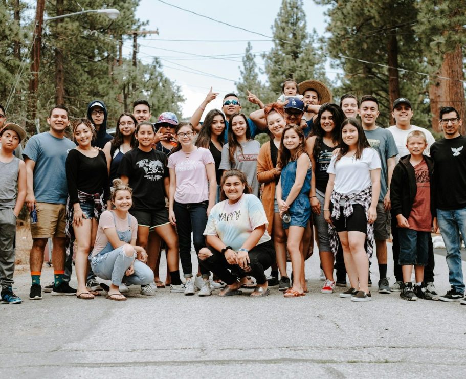 Groupe de jeunes souriants en plein air, entouré d'arbres, sur une route.