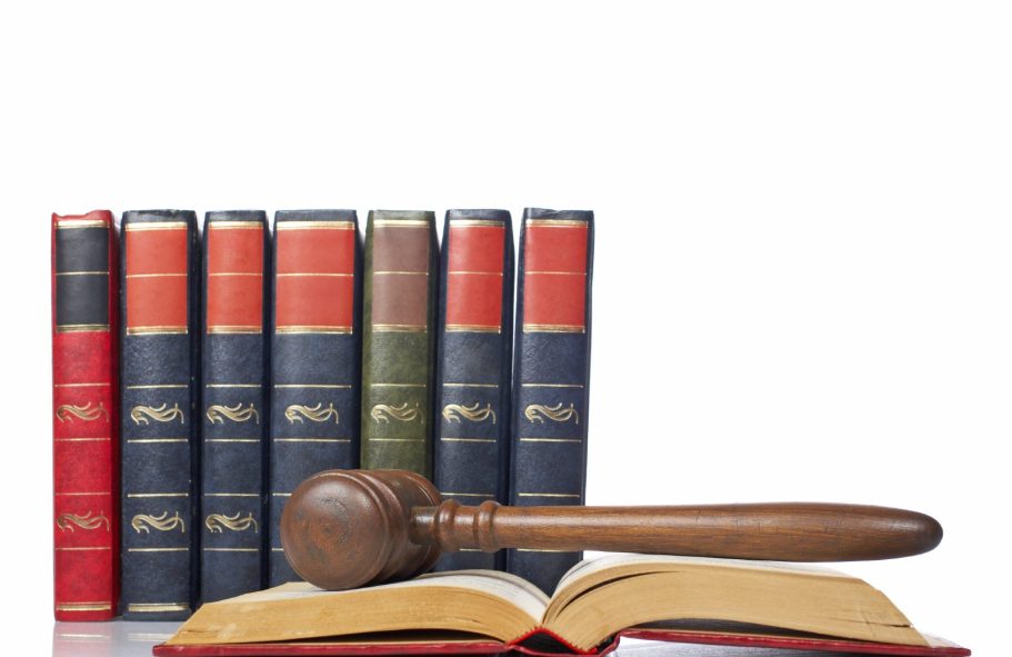 Une mallette en bois sur un livre, avec une bibliothèque de livres juridiques en arrière-plan.