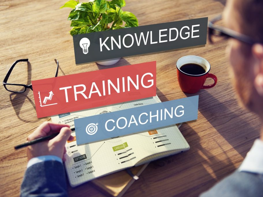 Un homme écrit sur un bloc-notes, entouré de mots clés : connaissance, formation, coaching.